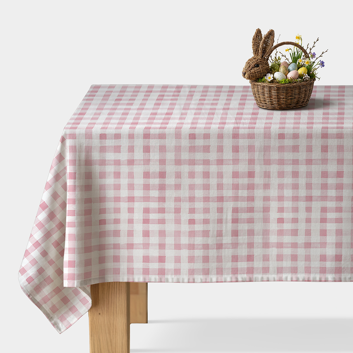 stół nakryty obrusом w różowo-białą kratę z koszykiem wielkanocnym z pisankami