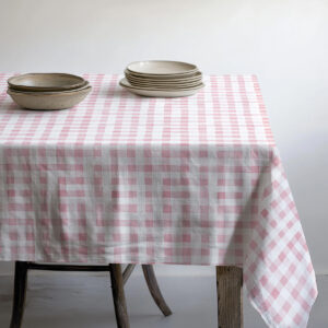 stos talerzy ustawiony na obrusie z delikatnym różowym wzorem kraty