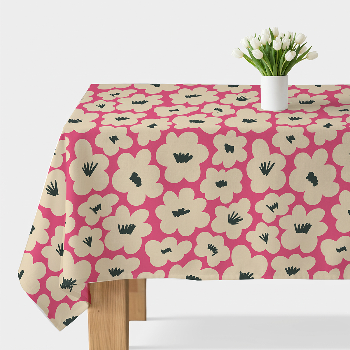 Stół nakryty obrusem z kremowymi kwiatami na malinowym tle z białym wazonem z tulipanami