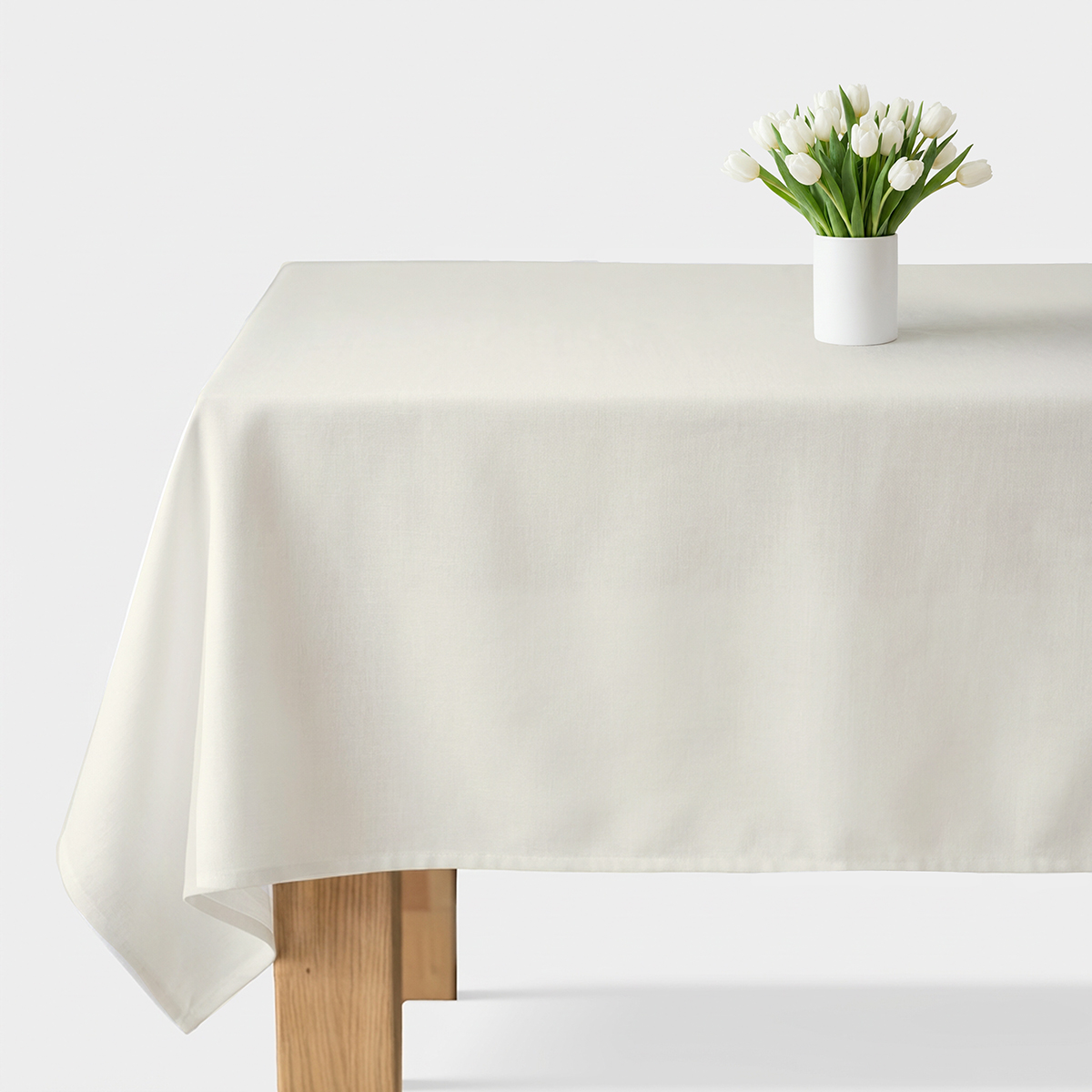 Kremowy gładki obrus na stole z wazonem białych tulipanów