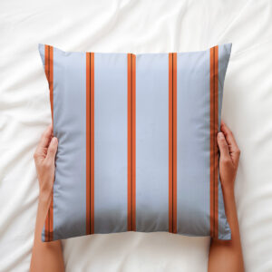 Widok od góry na poduszkę trzymaną w dłoniach, wyraźne pomarańczowe pasy