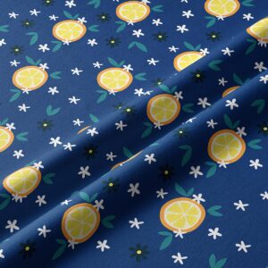 Zbliżenie tkaniny z plasterkami cytryny, zielonymi listkami i drobnymi białymi kwiatkami