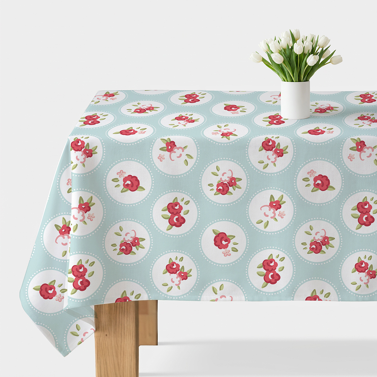 Obrus rozłożony na stole, miętowe tło z białymi medalionami i różowymi kwiatkami