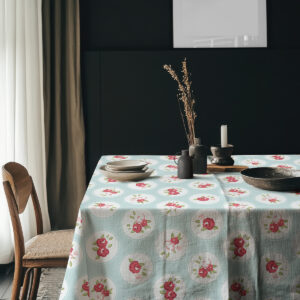 Stół nakryty obrusem w medaliony z dekoracjami i ceramicznymi naczyniami