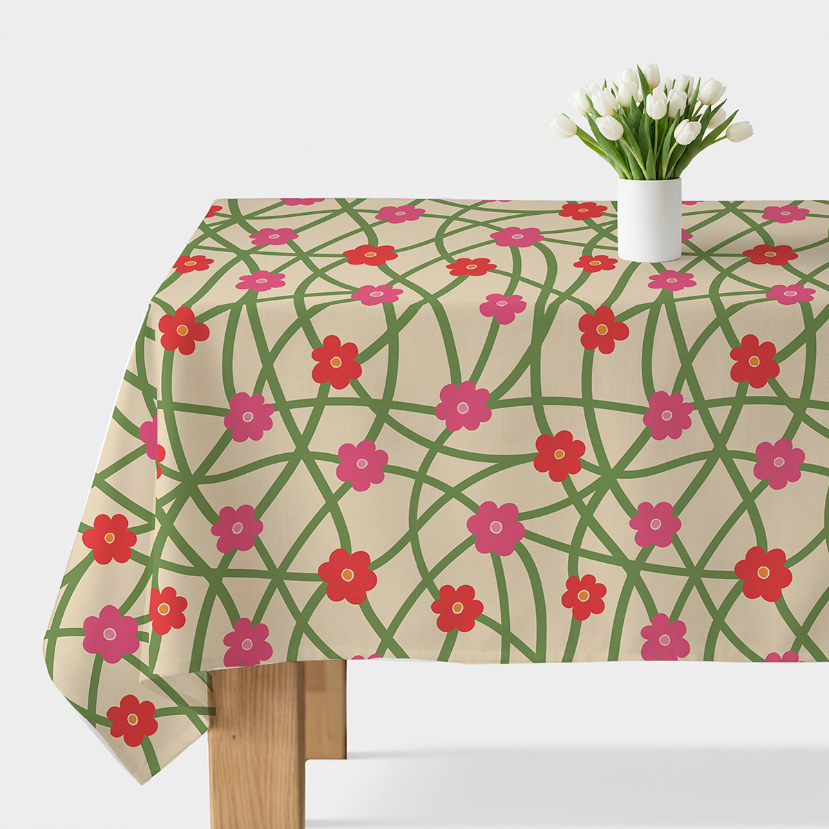 Obrus z kremowym tłem i siecią zielonych pnączy ozdobiony czerwono-różowymi kwiatami na stole z białym wazonem z tulipanami