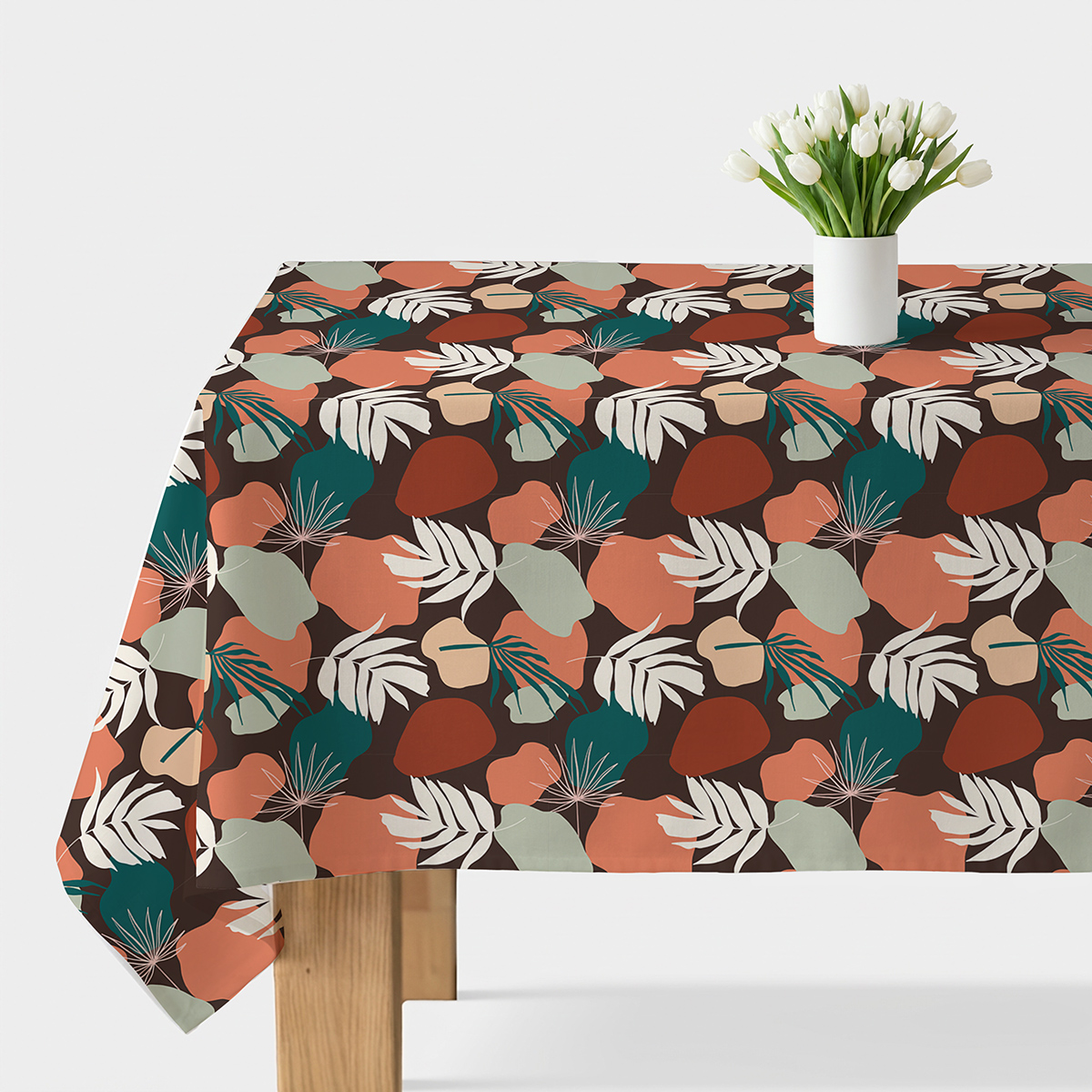 Obrus z liściastym, kolorowym wzorem rozłożony na stole z wazonem białych kwiatów