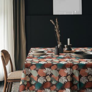 Aranżacja stołu z zastawą na obrusie w liściasty wzór w eleganckim wnętrzu