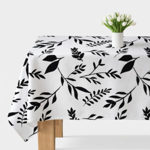 biało-czarny obrus z dużym motywem gałązek na stole udekorowany białym wazonem z tulipanami