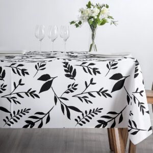 stylizowana scena śniadaniowa z obrusem w czarno-białe liście, filiżanką i dekoracją stołu