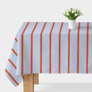 Obrus na stole jasnoniebieski z pionowymi pomarańczowymi pasami i wazon z białymi tulipanami