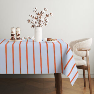 Stół udekorowany obrusem z pionowymi pasami oraz naczyniami i dekoracyjnymi gałązkami