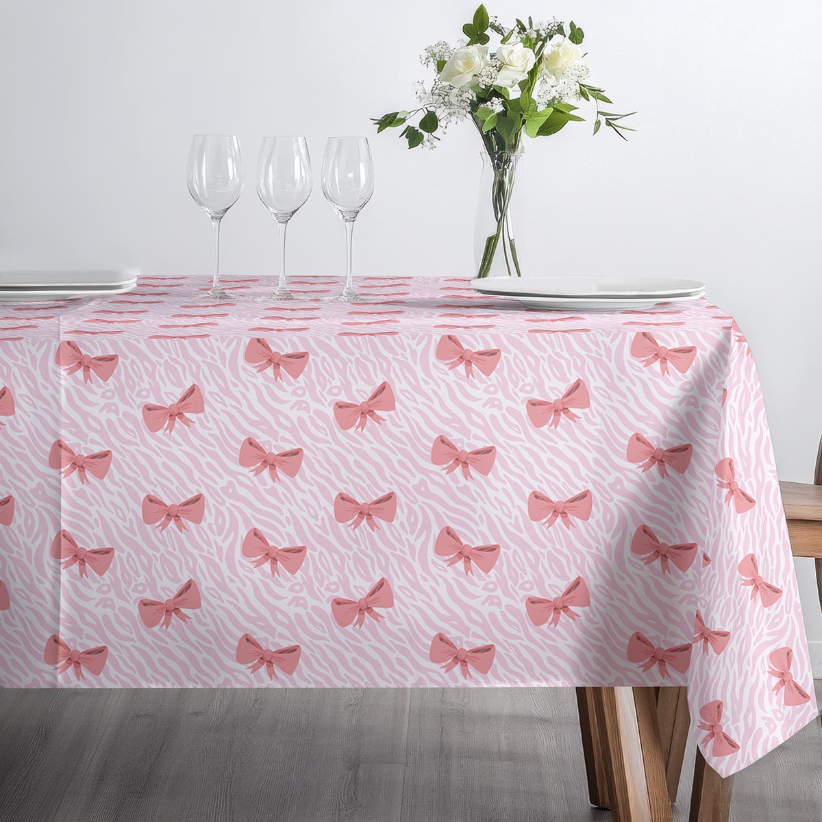 minimalistyczne ustawienie talerzy i kieliszków na obrusie z kokardkami