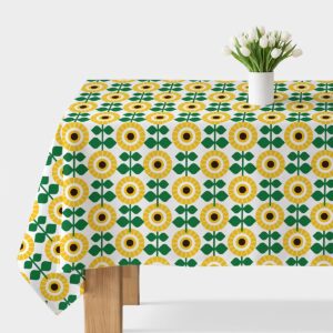 Obrus rozłożony na stole z wyraźnym geometrycznym wzorem słoneczników i białym wazonem z tulipanami