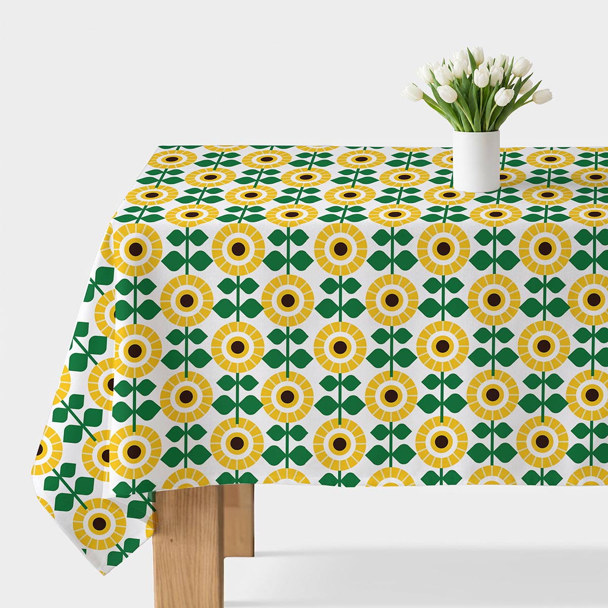 Obrus rozłożony na stole z wyraźnym geometrycznym wzorem słoneczników i białym wazonem z tulipanami