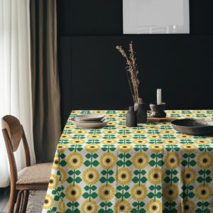 Aranżacja stołu w ciemniejszym wnętrzu z talerzami i dekoracjami na obrusie w żółto-zielony wzór