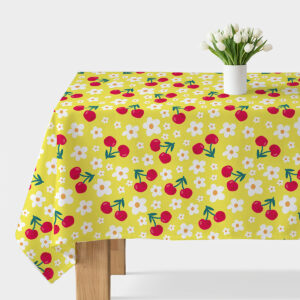 Obrus na stole z żółtym tłem zdobiony czerwonymi wiśniami i białymi kwiatkami