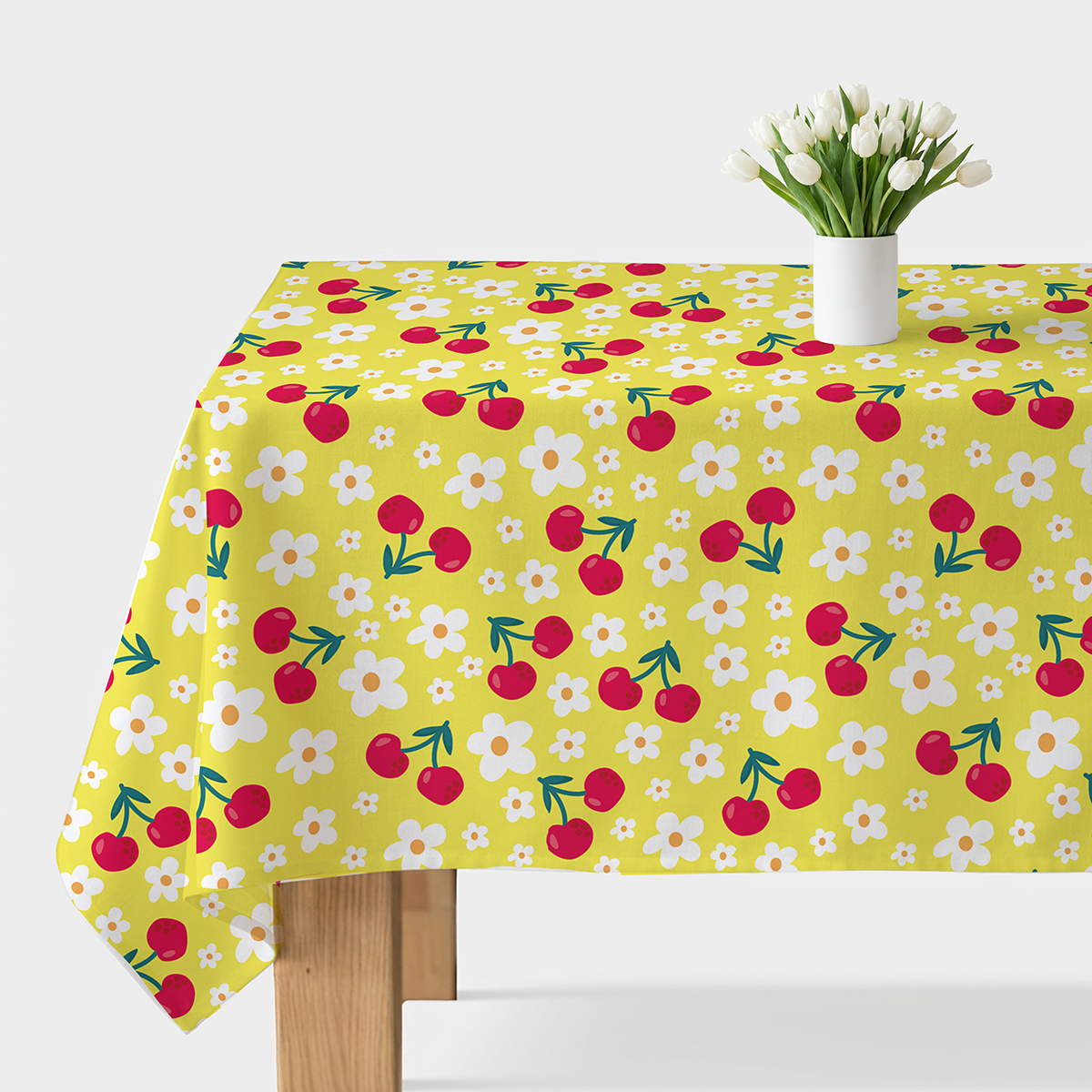 Obrus na stole z żółtym tłem zdobiony czerwonymi wiśniami i białymi kwiatkami