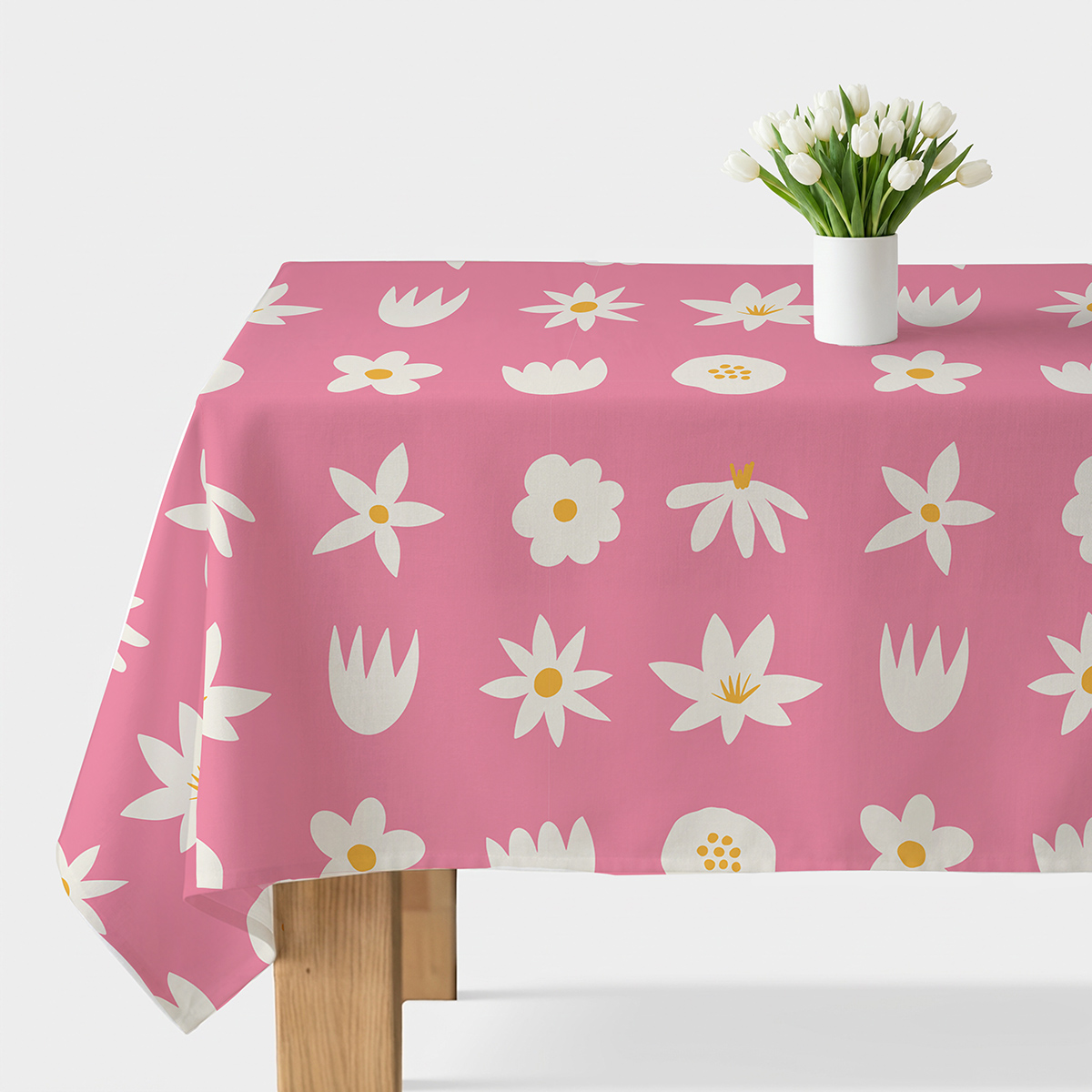 Obrus w różowym kolorze z białymi stylizowanymi kwiatami i żółtymi środkami na stole