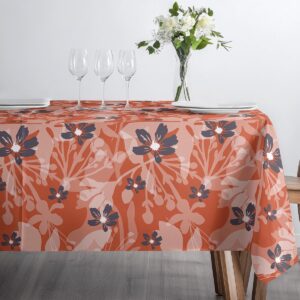 Nakryty stół z kieliszkami i talerzami na obrusie o botanicznym motywie