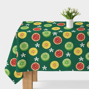Obrus z wzorem plasterków cytrusów na zielonym tle ułożony na stole, widok ogólny