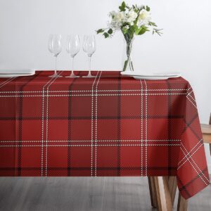 stół nakryty czerwonym obrusem w kratę z kieliszkami i wazonem z kwiatami