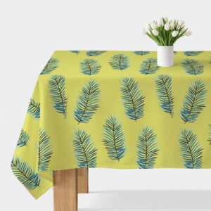 Obrus na stole z limonkowym tłem i niebieskimi liśćmi palmowymi, na środku biały wazon z tulipanami