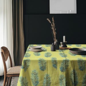Aranżacja stołu z talerzami i dekoracjami na obrusie z motywem liści palmowych