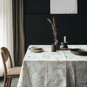 aranżacja stołu z obrus z akwarelowym wzorem na tle ciemnej ściany z ceramiką i świecą