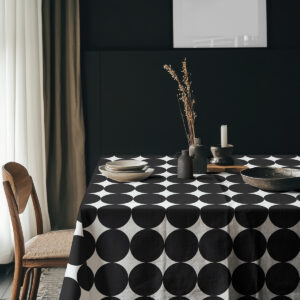 Aranżacja stołu z obrusie w czarne kółka w ciemnym wnętrzu i prostą zastawą