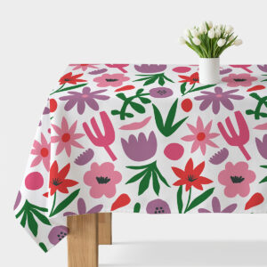 Obrus z dużym, kolorowym, graficznym motywem kwiatowym rozłożony na stole z białym wazonem