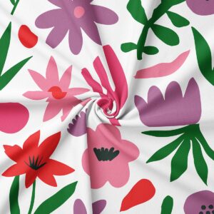 Zbliżenie na tkaninę i nadruk pokazujące stylizowane tulipany, gwiazdki i liście w różu, czerwieni i zieleni