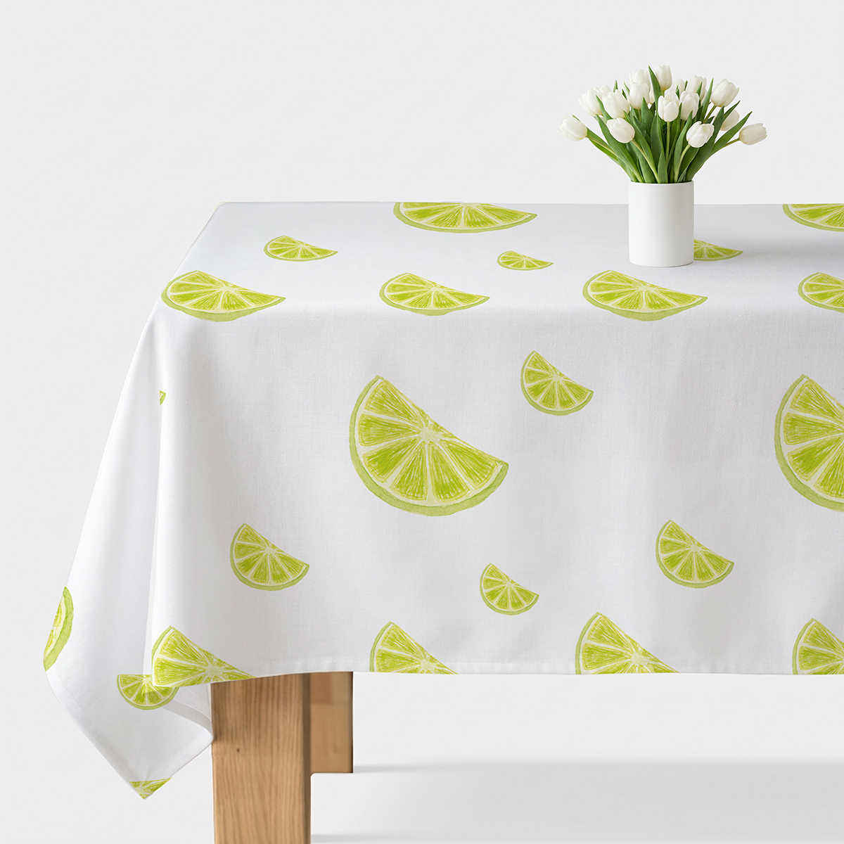 biały obrus z rozrzuconymi limonkowymi plasterkami na stole z wazonem białych tulipanów