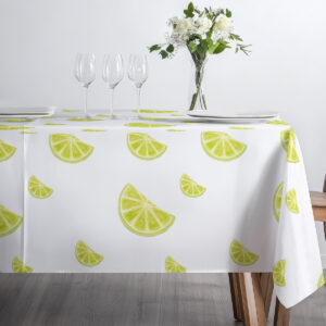 blat stołu z filiżanką i imbrykiem na jasnym obrusie ozdobionym plasterkami limonki