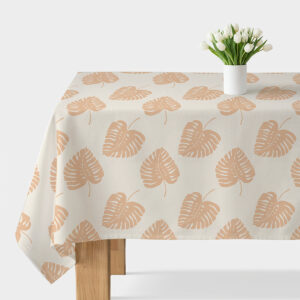 obrus na stole z dużym motywem liści monstery i białym wazonem z tulipanami