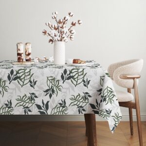 Widok stołu w jadalni z obrusem o roślinnym motywie i drewnianym krzesłem w tle