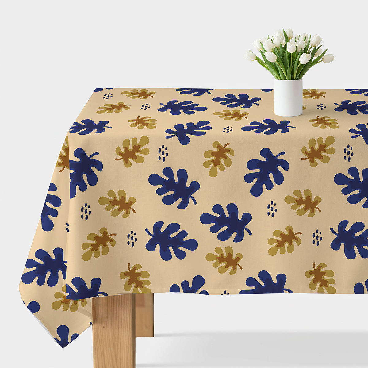obrus na stole z kremowym tłem i motywem granatowych i złotych liści z białymi tulipanami w wazonie