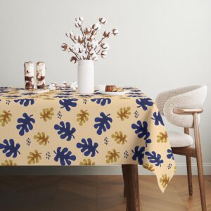 fragment stołu z widocznym rogiem obrusa i powtarzającym się wzorem liści