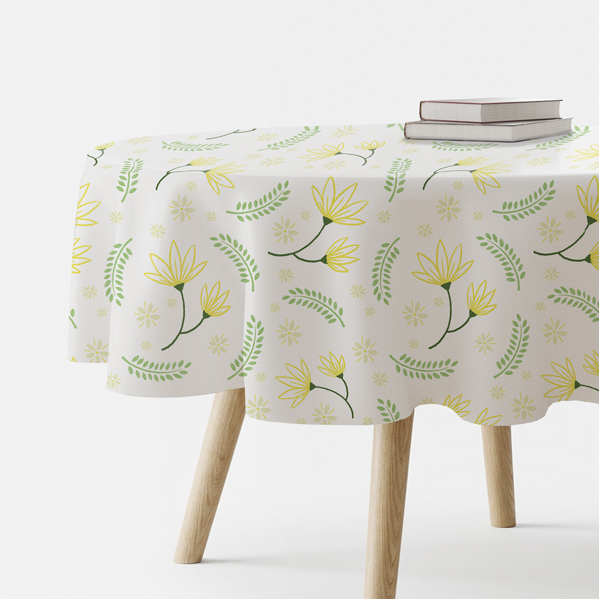 okrągły obrus na stole z motywem żółtych kwiatów i zielonych listków, widok z boku z książkami na stole