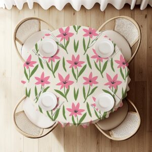 Widok z góry na nakryty stół z okrągłym obrusem w różowy wzór i cztery miejsca przy stole