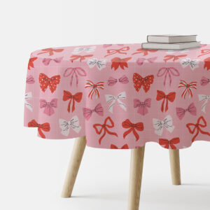 okrągły różowy obrus z wzorem czerwonych i białych kokardek na stole z drewnianymi nogami