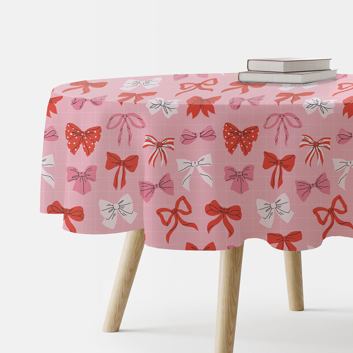 okrągły różowy obrus z wzorem czerwonych i białych kokardek na stole z drewnianymi nogami