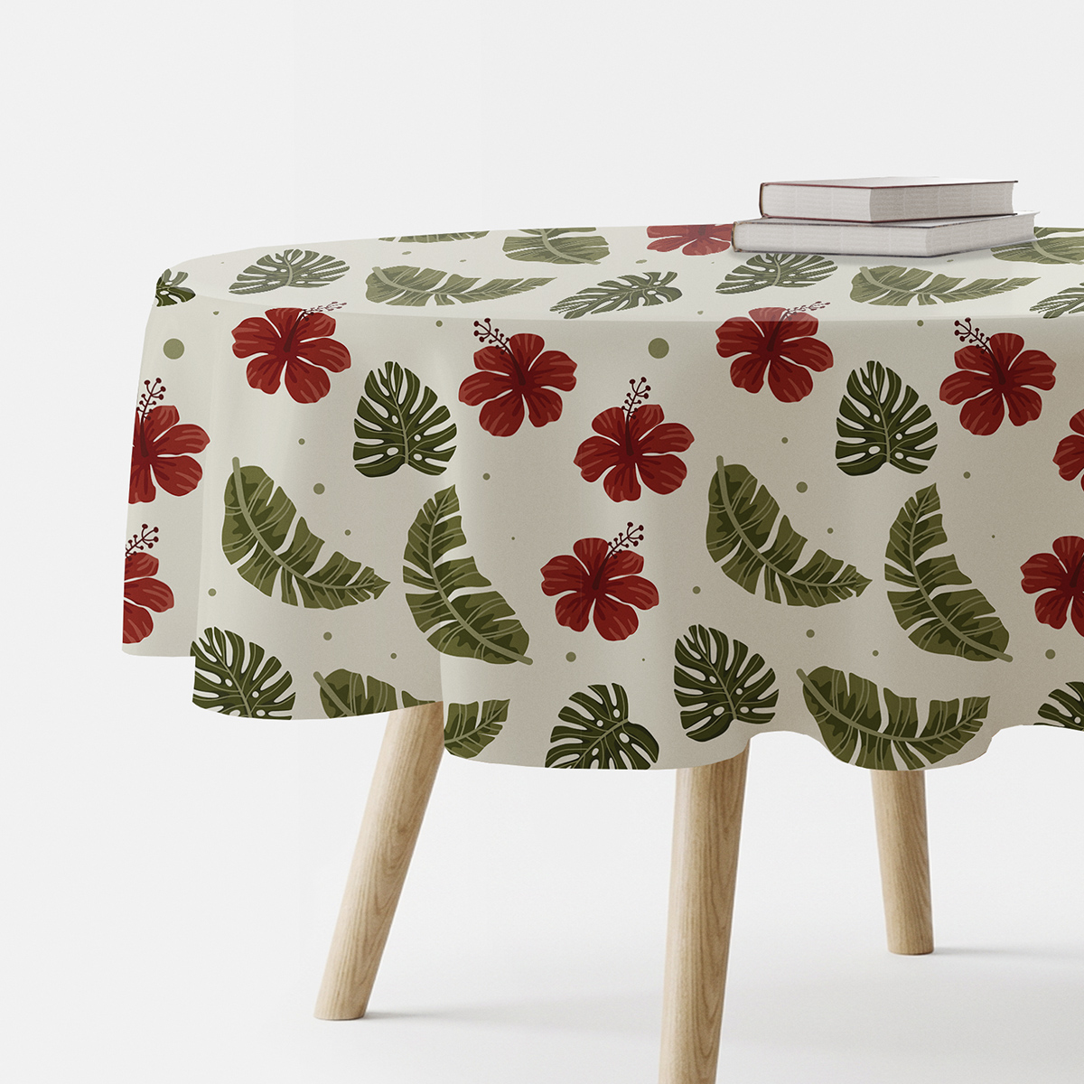okrągły obrus na stole z czerwonymi hibiskusami i zielonymi liśćmi na kremowym tle