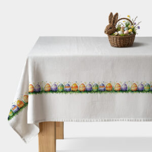 Świąteczny obrus z akwarelowym motywem pisanek rozłożony na stole z koszykiem dekoracyjnym