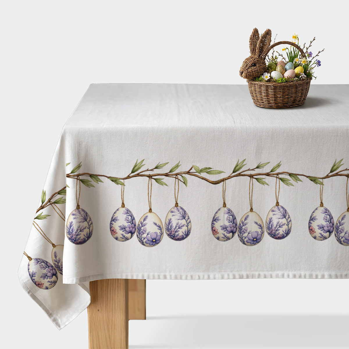 główny widok świątecznego obrusu z motywem wiszących pisanek na gałązce na białym stole