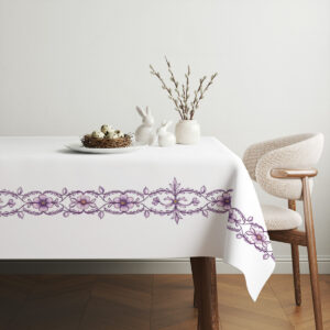 aranżacja stołu ze świątecznym obrusem, talerz z gniazdem i ceramicznymi zającami obok