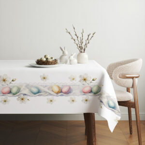 Aranżacja stołu ze świątecznym obrusem, koszyk z pisankami i dekoracje w tle