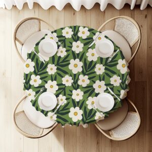 Widok z góry na okrągły obrus z rozmieszczonymi białymi kwiatami i liśćmi