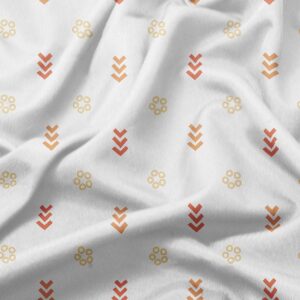 Zbliżenie na tkaninę z delikatnym wzorem kółeczek i strzałek w odcieniach pomarańczowym i żółtym