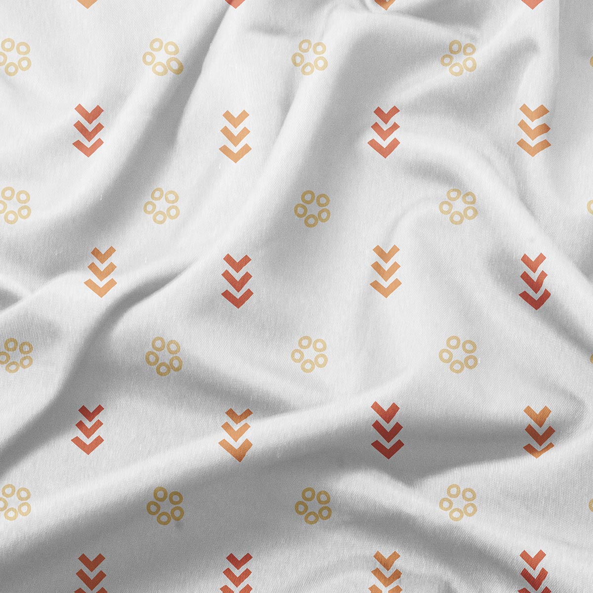 Zbliżenie na tkaninę z delikatnym wzorem kółeczek i strzałek w odcieniach pomarańczowym i żółtym