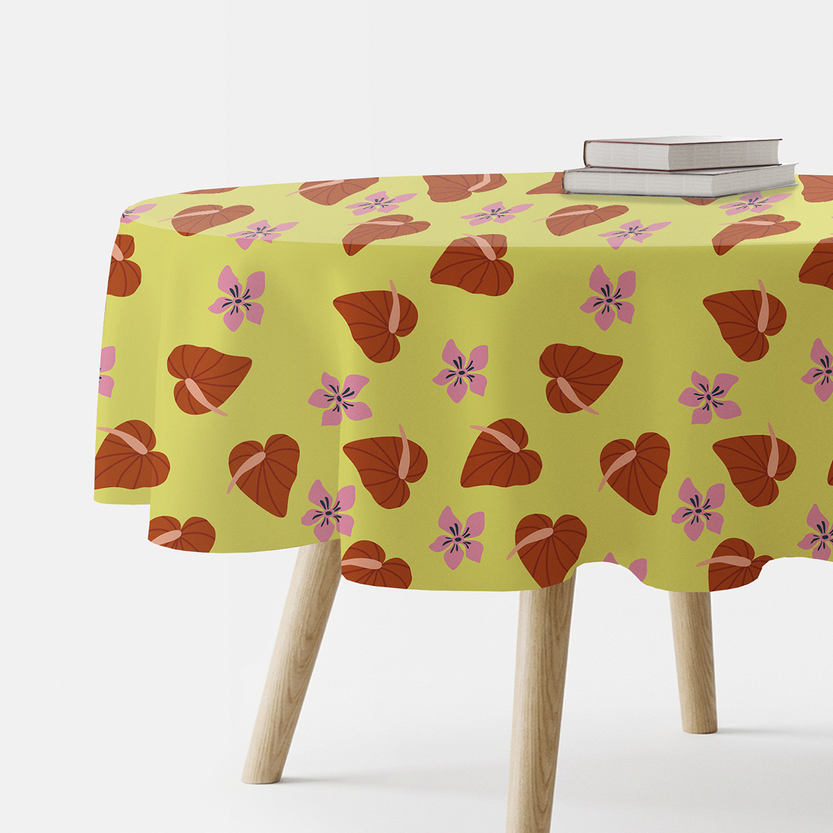 Okrągły obrus z liściastymi sercami i różowymi kwiatami na jasnym zielonym tle, ujęcie stołu z książkami